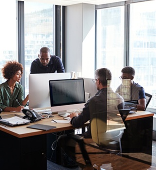 four people working around a desk on their computers